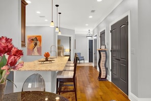 A modern kitchen with a central island, pendant lighting, and a dining area with chairs. - Amazing Location on Bay Street by Southern Belle (Savannah)
