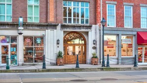 A brick building with a large arched entrance and a red awning. - Amazing Location on Bay Street by Southern Belle (Savannah)