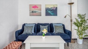 En moderne stue med en mørkeblå sofa, et hvidt sofabord og to billeder hængt på væggen.