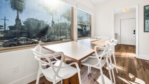 Une pièce moderne avec une grande fenêtre, une table en bois et des chaises blanches.