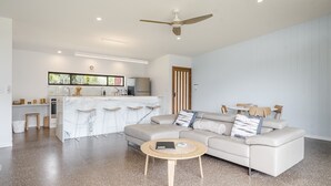 A modern living room with a sofa, coffee table, and a kitchen area with a bar. - Take it easy at this unique and tranquil getaway. (Tintenbar)