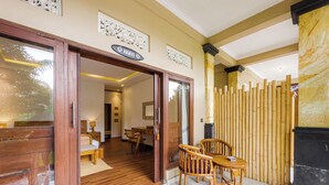 A hotel room with a wooden floor, a desk, two chairs, and a bed. - Ubud Shanti Rice Field House By Supala (Ubud)