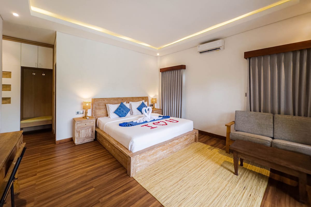 Une chambre d’hôtel avec un lit en bois, un canapé, un bureau et une armoire.