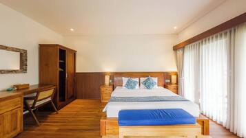 A hotel room with a wooden bed, bedside tables, a desk, and a wardrobe.