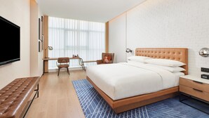 A hotel room with a large bed, a desk, a chair, a TV, and a clock on the nightstand. - Four Points By Sheraton Xi’An High-Tech Zone (Xi'an)