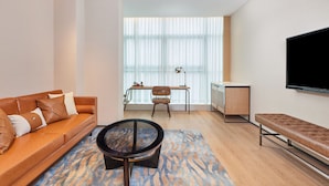 A modern living room with a sofa, a round coffee table, a bench, a TV, and a desk with a chair. - Four Points By Sheraton Xi’An High-Tech Zone (Xi'an)