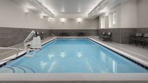 Une piscine intérieure moderne, avec une eau d’un bleu limpide, des murs carrelés et un plafond doté d’un éclairage encastré.