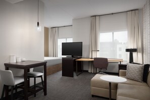 A modern hotel room with a flat-screen TV, a desk, a sofa, and a small round table. - Residence Inn by Marriott Kenwood Cincinnati (Cincinnati)