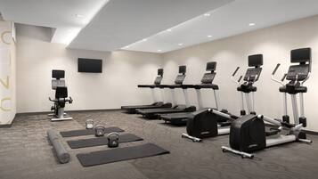 A gym with treadmills, elliptical machines, and free weights.