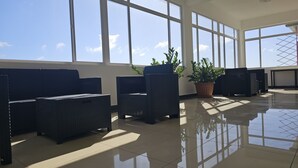 A spacious indoor area with large windows, wicker furniture, and a potted plant. - 05-Experience contemporary luxury at Prince APT, 20-minute stroll from the beach (Willemstad)