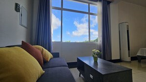 A room with a sofa, a small table with a vase, a standing heater, and a window with curtains. - 05-Experience contemporary luxury at Prince APT, 20-minute stroll from the beach (Willemstad)