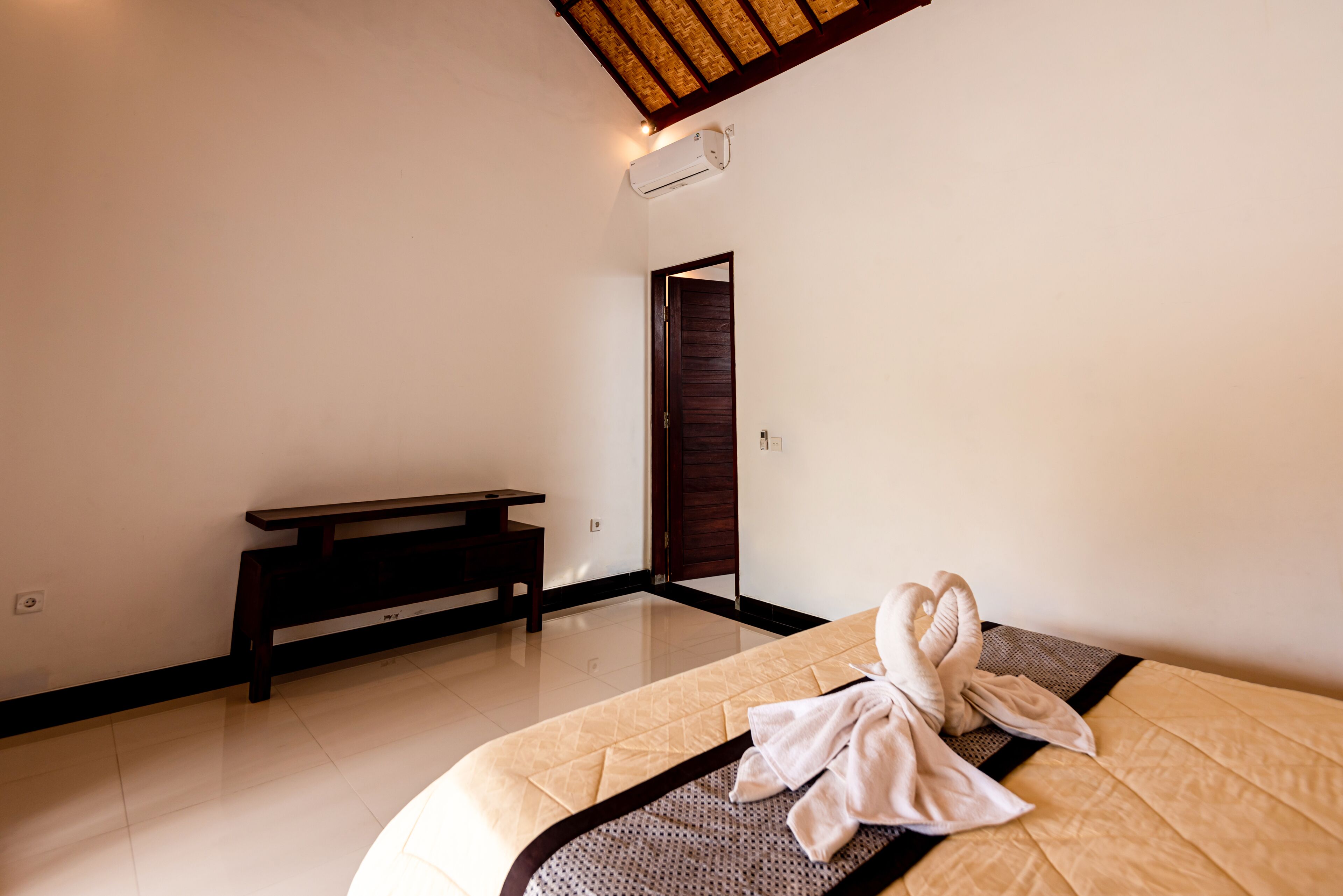 Een hotelkamer met een bed, een bankje en een deur.