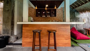 Eine Bar mit Hockern, einer Ziegelwand und einem reetgedeckten Dachstuhl.
