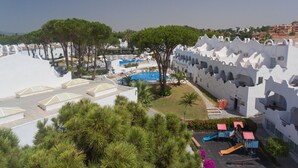 Ein Resort mit Poolbereich, Spielplatz und einem Gebäude mit Bögen.