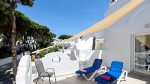 En takterrass med vita väggar, en pergola och två blå loungestolar.