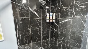 A bathroom with a black marble wall, a white bathtub, and a shower curtain. - Cozy basement apartment in Brampton  (Brampton)