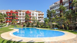 A swimming pool surrounded by a stone deck, with a building featuring balconies and red accents in the background. - Amazing place with large terrace and BBQ (Mijas Costa)