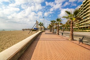 A beachside promenade with palm trees, a paved walkway, and a beachfront. - Cozy place in Fuengirola - 50m to the beach (Fuengirola)