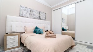A bedroom with a large bed, a nightstand, a mirror, and artwork on the wall. - Fabulous townhouse - great resort facilities (Marbella)