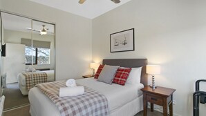 A hotel room with a bed, bedside tables, a mirror, and a framed picture on the wall. - Apres - Dinner Plain (Dinner Plain)
