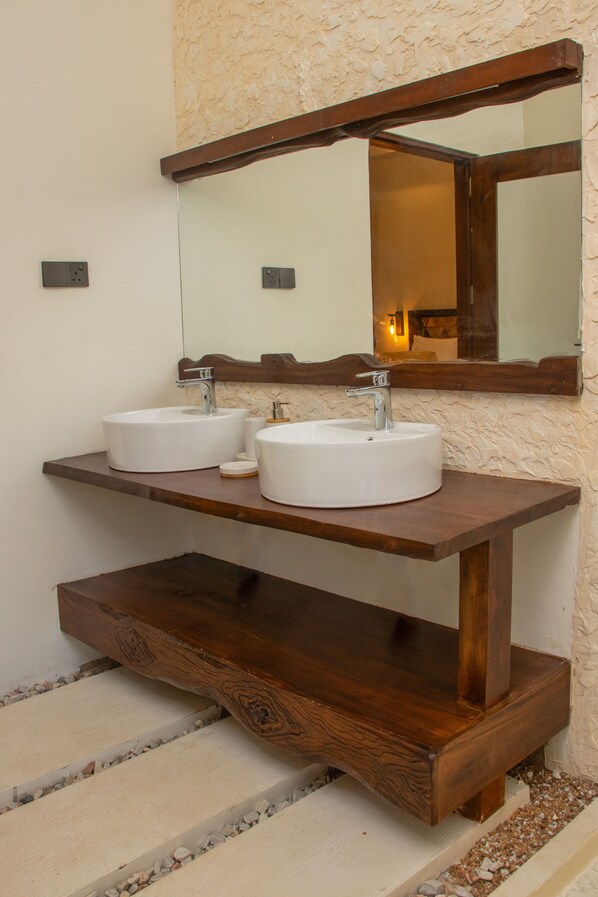 A bathroom with two white sinks, a wooden vanity, and a large mirror above the sinks.