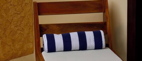 A wooden chair with a white cushion and a blue and white striped pillow.