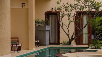 Un área de piscina con superficie de agua cristalina, rodeada de paredes color beige y mobiliario de madera.
