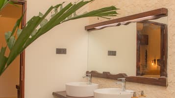 A bathroom with two sinks, a wooden vanity, a large mirror, and a potted plant.
