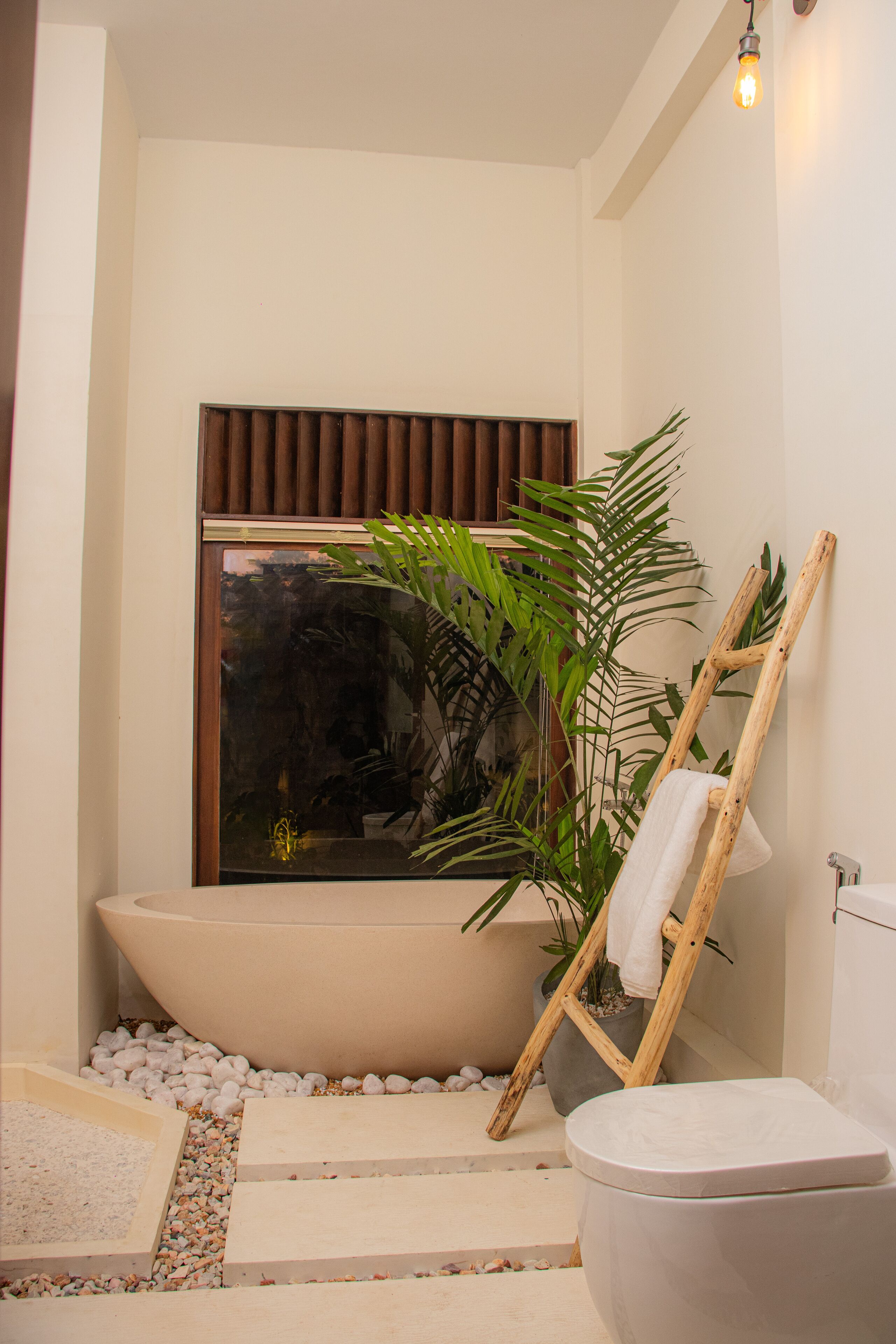 A bathroom with a bathtub, toilet, and a window with blinds.
