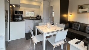 Eine moderne Küche mit integrierten Geräten, ein Essbereich mit Tisch und Stühlen sowie ein Wohnbereich mit Sofa und Couchtisch.
