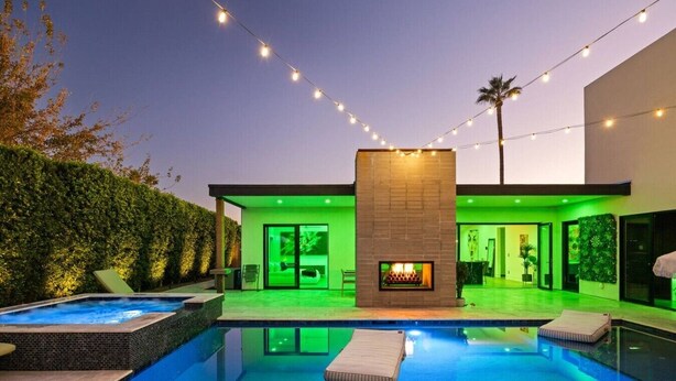 Une maison moderne dotée d’une piscine, d’une cheminée et de guirlandes lumineuses.