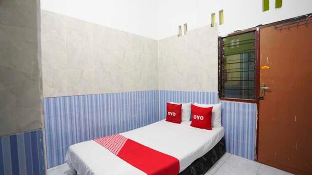 Ein Einzelbett mit rotem und weißem Bettbezug, zwei rote Kissen und eine blaue und weiße, gestreifte Wand.