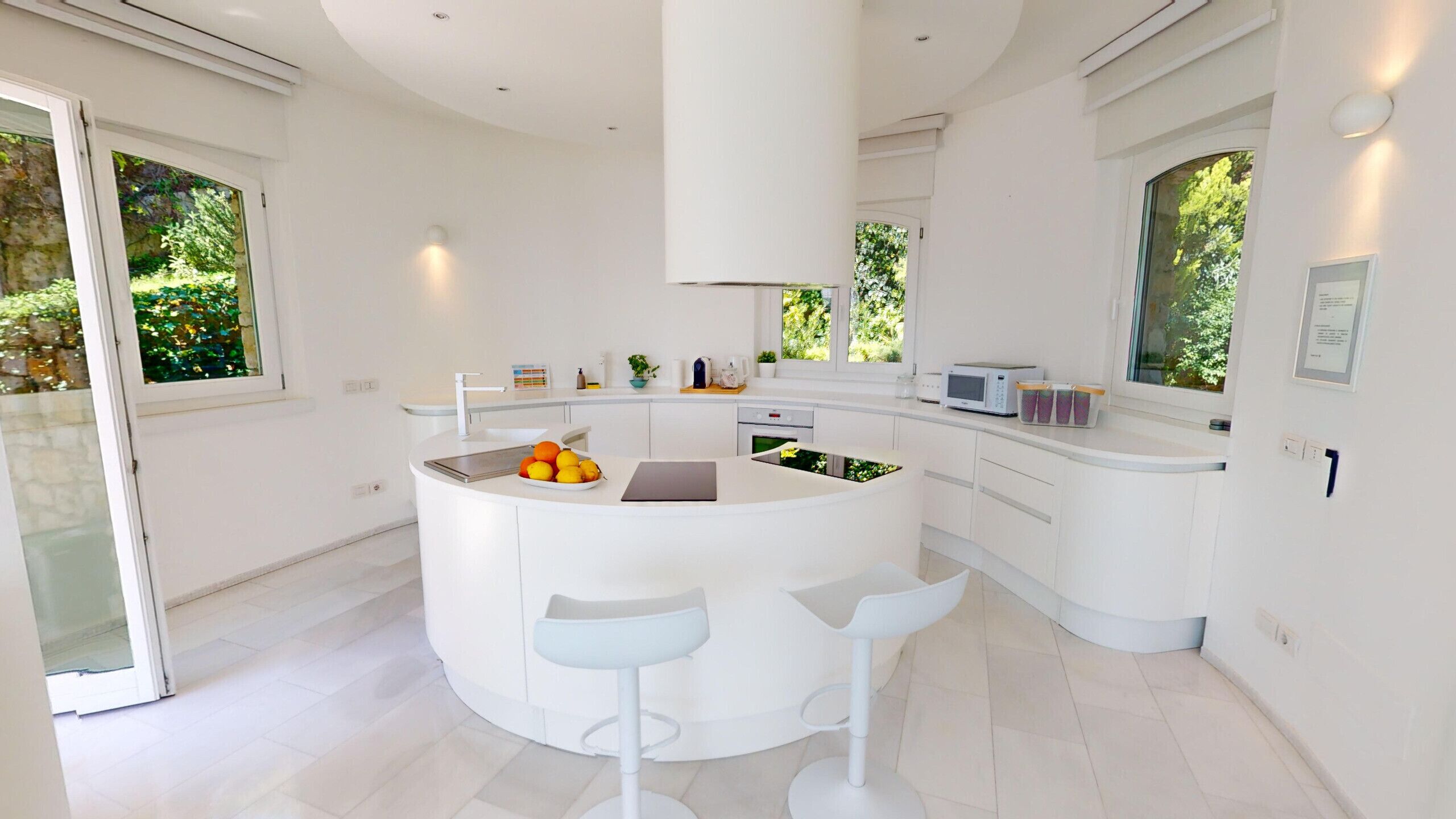 Una cocina moderna con una isla central, armarios blancos y un amplio ventanal que proporciona luz natural.