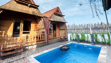 Una cabaña de madera con piscina, terraza de madera y jardín vallado.