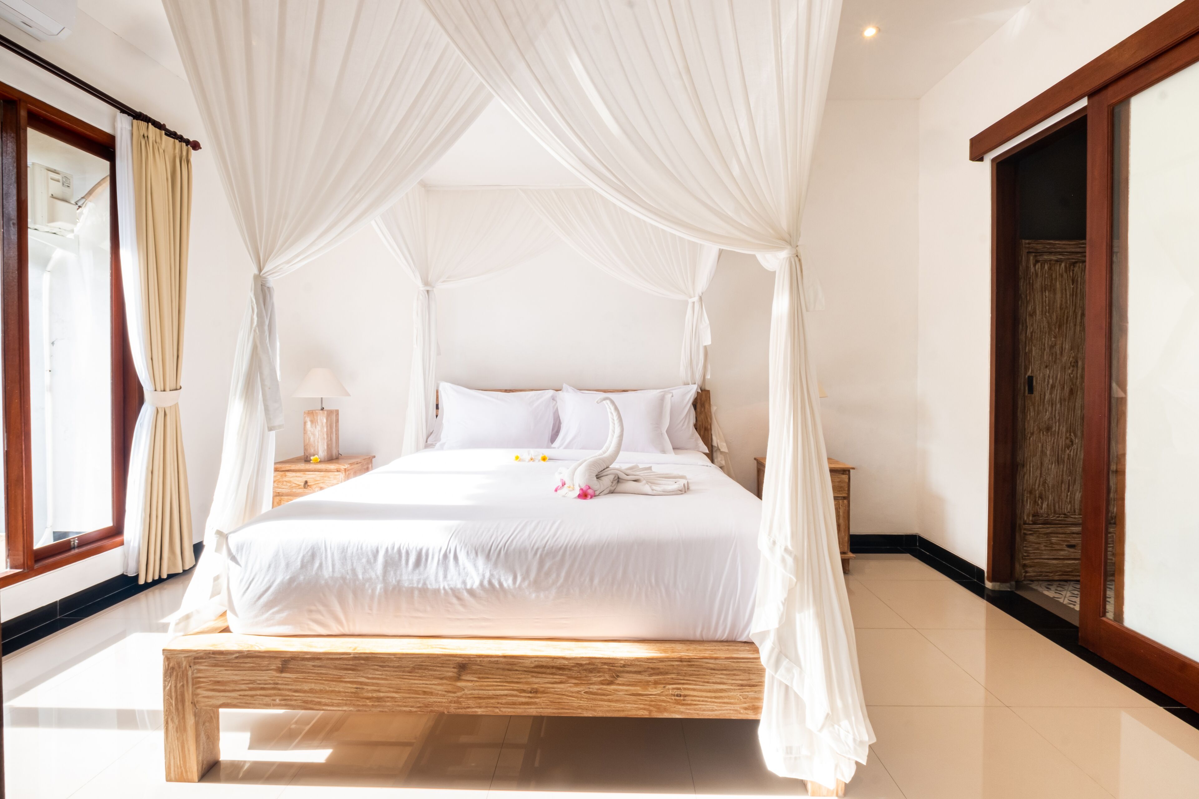 A spacious bedroom with a canopy bed, wooden headboard, and a bedside table with a lamp.