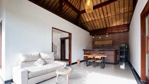 A modern living room with a sofa, a round coffee table, and a dining area with chairs and a table.