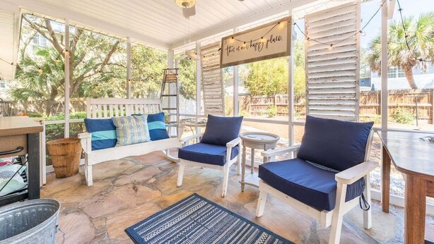 A covered patio with white furniture, a ceiling fan, and a sign that reads 'this is our happy place.' - Family Tides | Pet-Friendly East Beach Cottage Near Gould's Inlet on St. Simons Island (Saint Simons Island)
