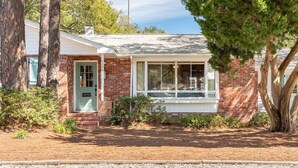 A single-story brick house with a front door, a window, and a small porch area. - Family Tides | Pet-Friendly East Beach Cottage Near Gould's Inlet on St. Simons Island (Saint Simons Island)