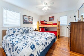 A bedroom with a bunk bed, a wooden dresser, a ceiling fan, and a painting on the wall. - Family Tides | Pet-Friendly East Beach Cottage Near Gould's Inlet on St. Simons Island (Saint Simons Island)