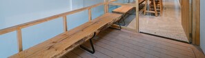 A wooden bench on a balcony with a glass railing and a concrete floor. - CityHouse VIBE Abora (Ho Chi Minh City)