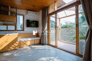 A modern apartment with a wooden ceiling, a large sliding glass door to a balcony, a built-in bench, and a flat-screen TV mounted on the wall. - CityHouse VIBE Abora (Ho Chi Minh City)