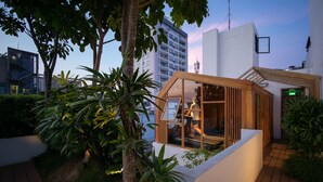 Un hotel moderno con una sala acristalada, rodeado de exuberante vegetación y una terraza de madera.