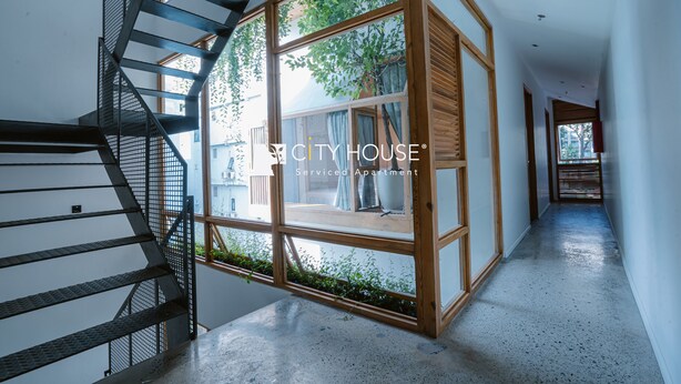 Un interior moderno con una escalera en espiral, un ventanal con vistas a zonas verdes y un suelo limpio y pulido.