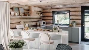 A modern kitchen with a central island, white appliances, and a view through a large window.