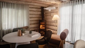 A cozy room with a round table, chairs, a fireplace, and a lamp.