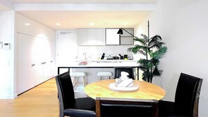 A modern kitchen with white cabinets, a central island, and a dining area with a wooden table and black chairs.