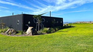 A modern building with a dark exterior, surrounded by a well-maintained grassy area and a few large rocks.