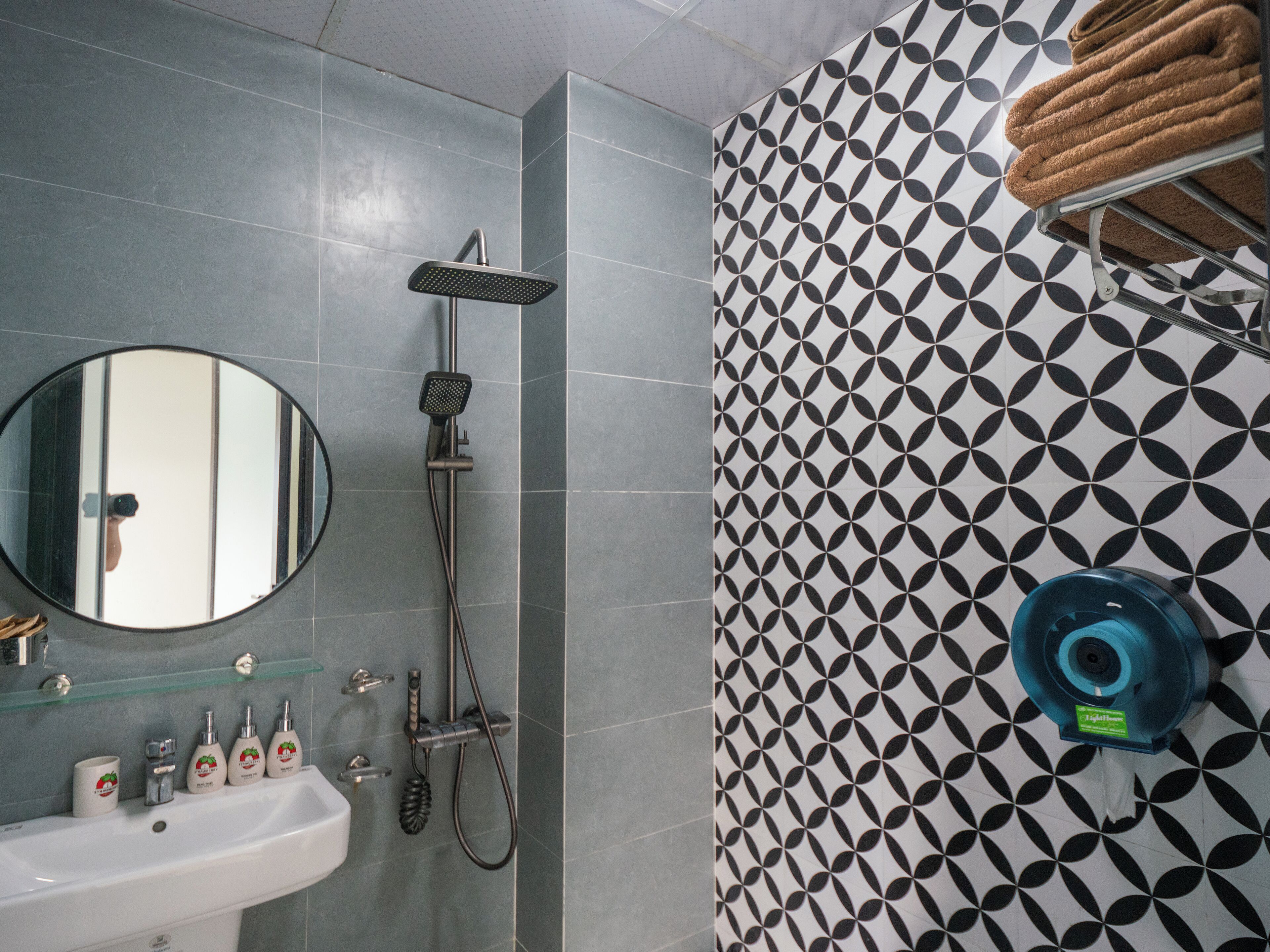 A bathroom with a sink, mirror, shower, and patterned tiles.