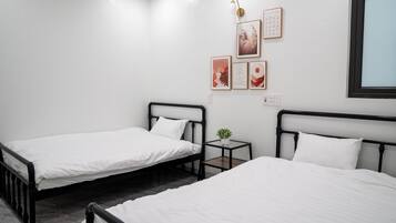 A bedroom with two single beds, a small bedside table with a plant, and wall art.