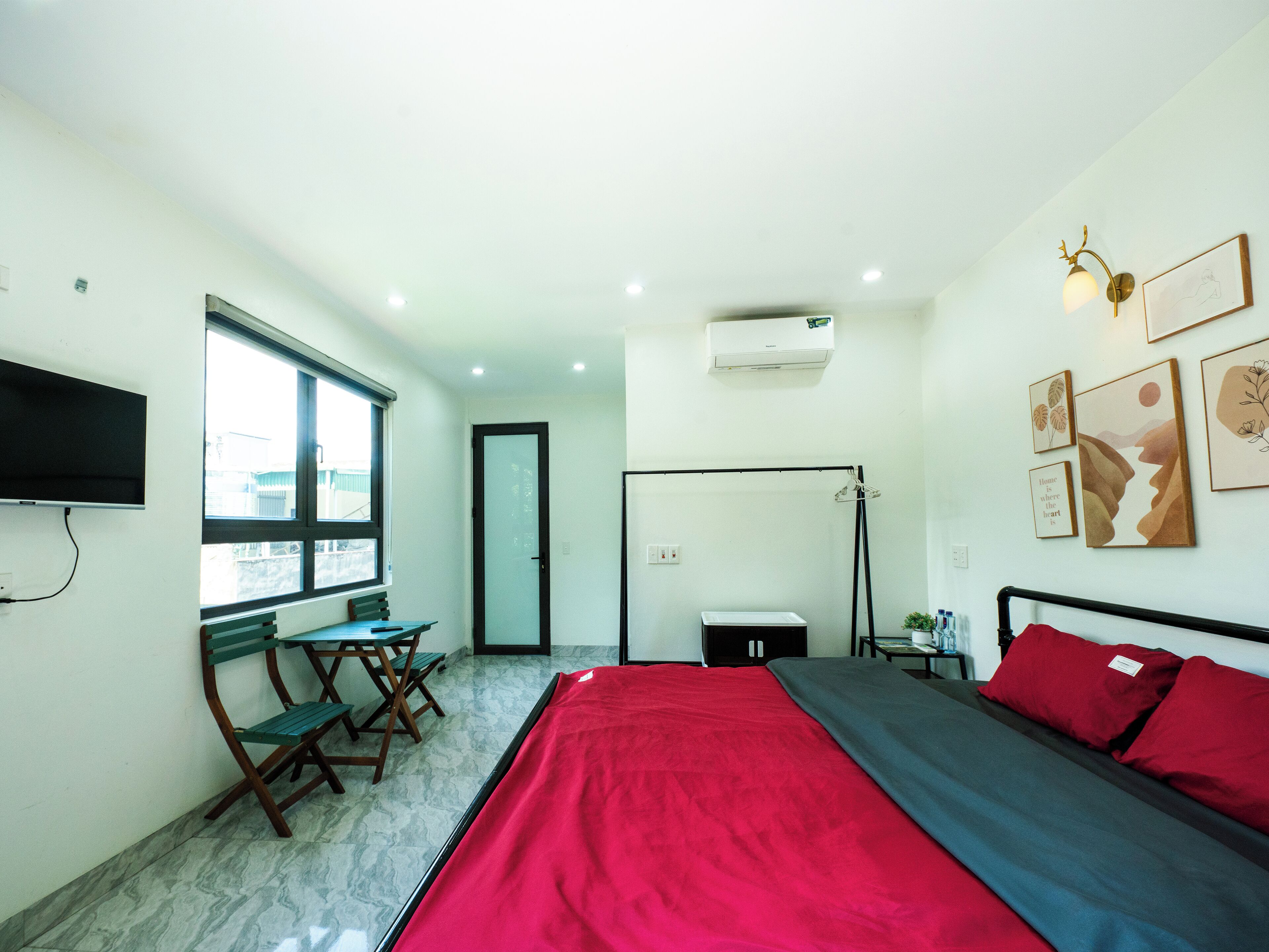 Ein Schlafzimmer mit Bett, Schreibtisch, Stuhl, Fenster und Bildern an der Wand.